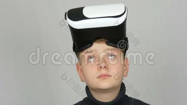 带着虚拟现实或虚拟现实眼镜的青少年男孩，他的头上戴着虚拟现实眼镜，在演播室的白色背景下玩得很开心